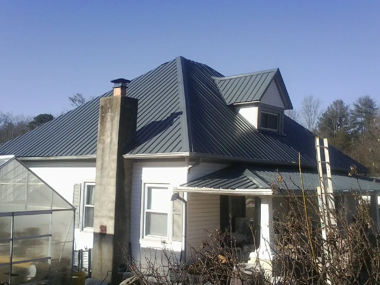 Dark blue standing seam metal roof on a white farmhouse with dormer — Slate & Tile Roof Repair by Roofing Brothers in Ponderay