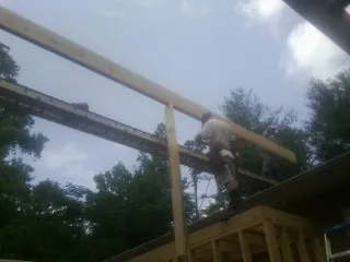 Carpenter setting a ridge beam over a new addition frame — Ice Dam Removal by Roofing Brothers in Ponderay