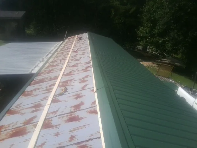 Old rusted panels beside newly installed green metal roofing — Wind Damage Roof Repair by Roofing Brothers in Ponderay