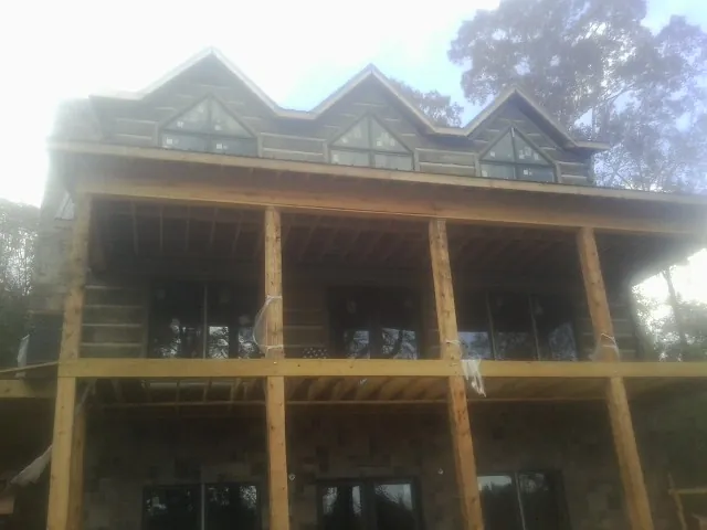 Dormers and porch framing on a large log home under construction — Roof Coating work by our crew in Ponderay