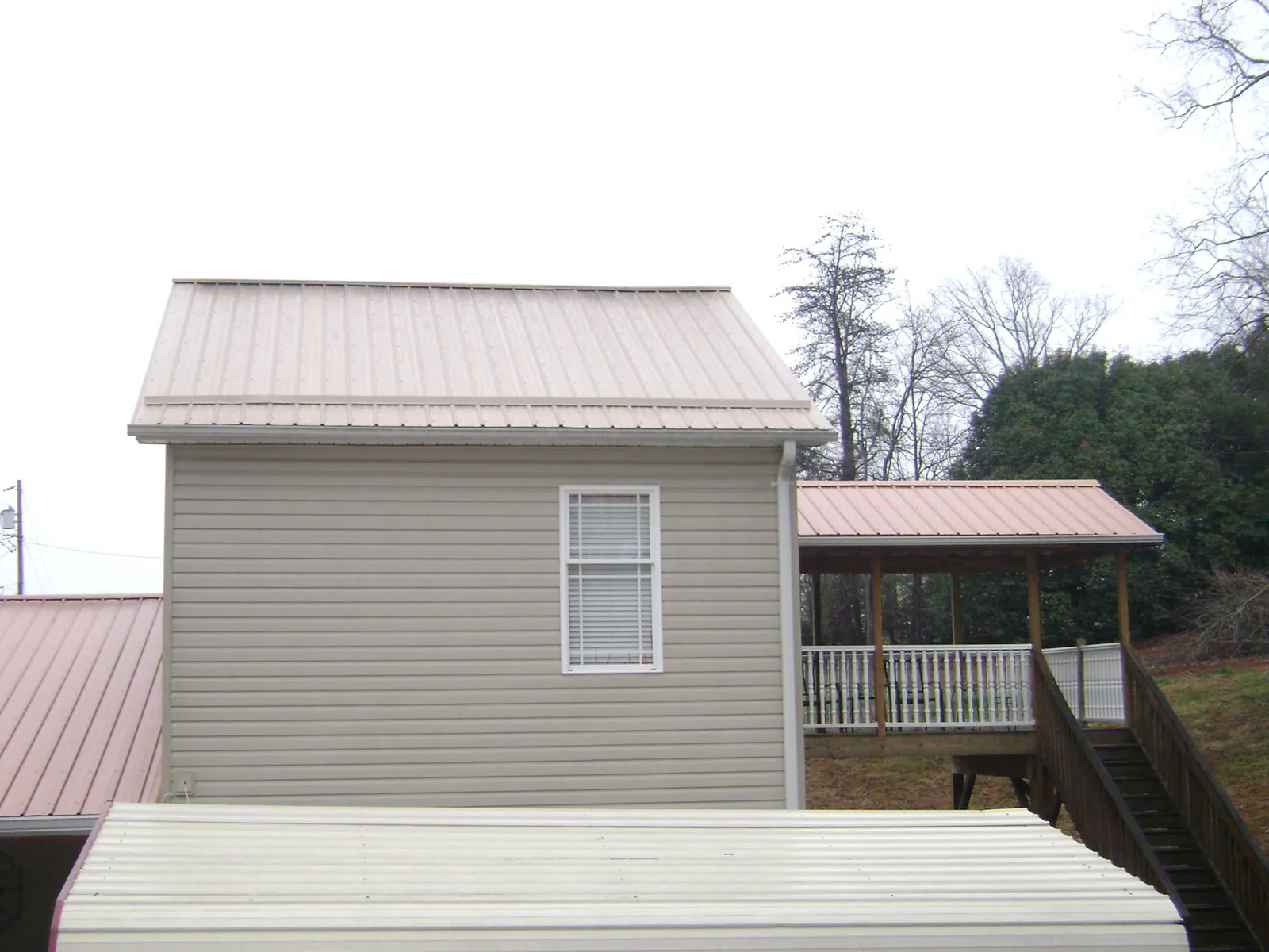 Tan metal roofs on a two story addition and attached porch, from a Roof Replacement job in Ponderay