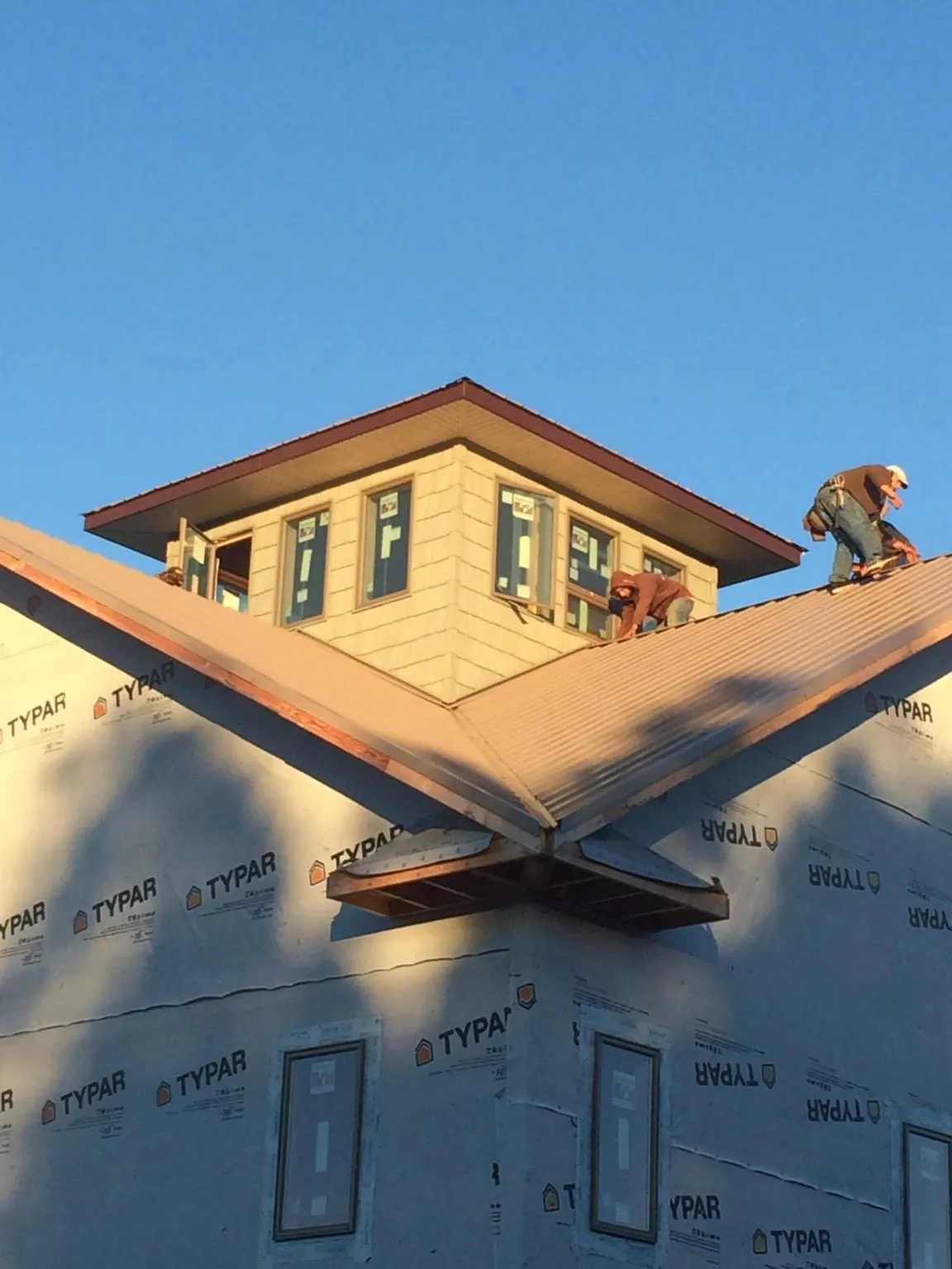Roofers working around a rooftop cupola on a new metal roof at sunset — Roof Waterproofing in Ponderay by Roofing Brothers